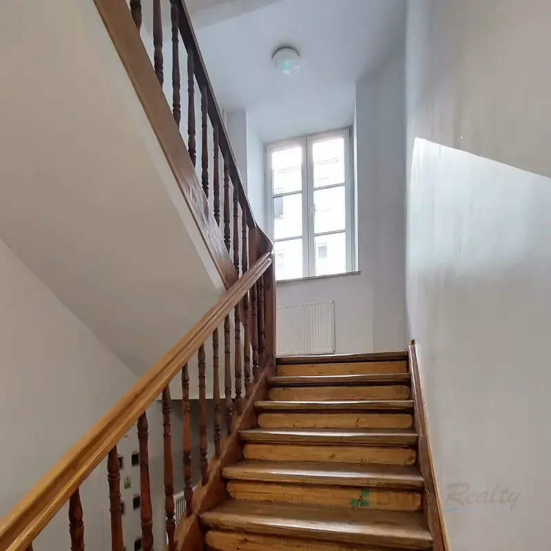 Jasne schody w kamienicy prowadzące do okna z naturalnym światłem